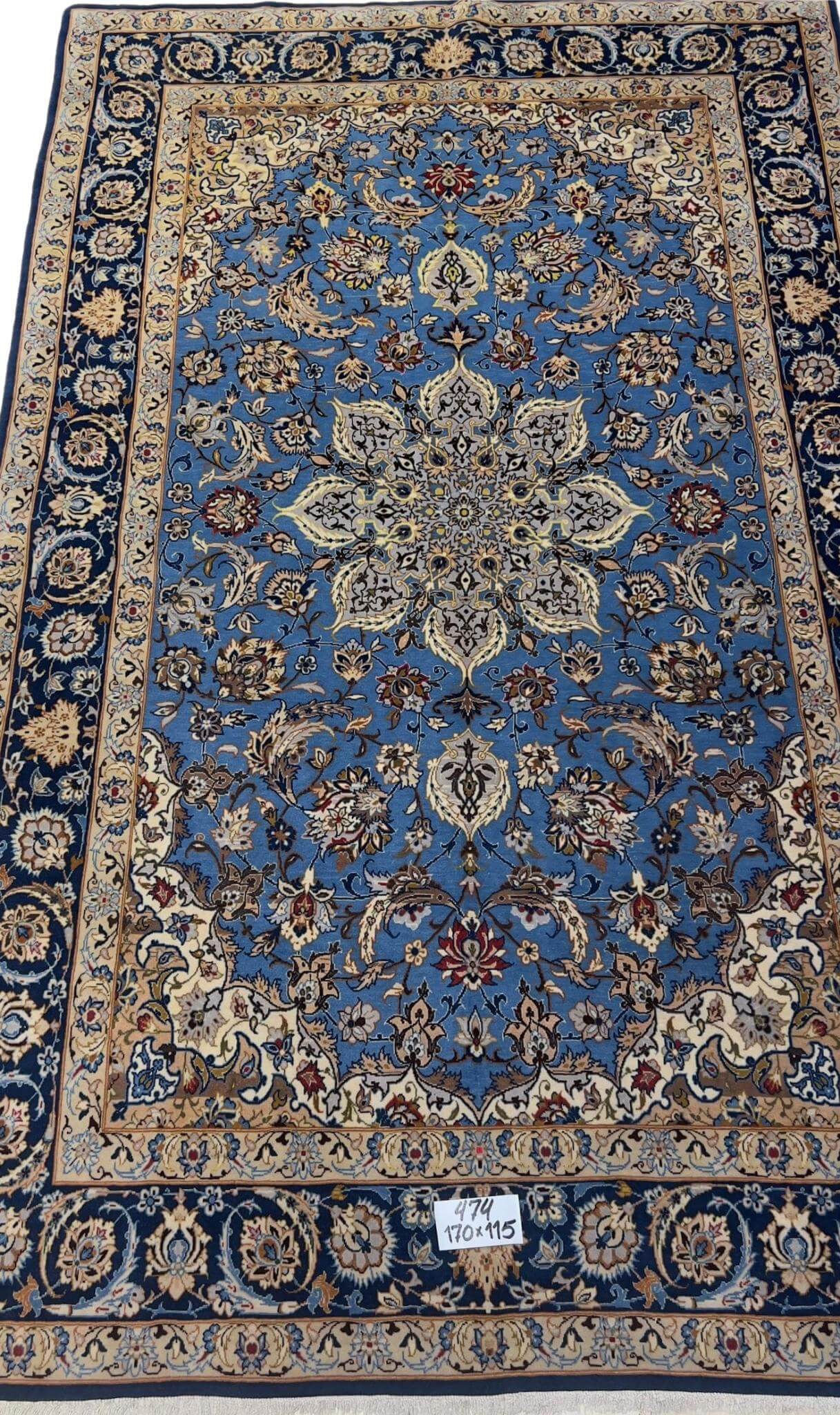 "Hand-knotted blue Persian rug from Isfahan, 170x115 cm, showcasing intricate floral and medallion designs in a wool and silk blend."